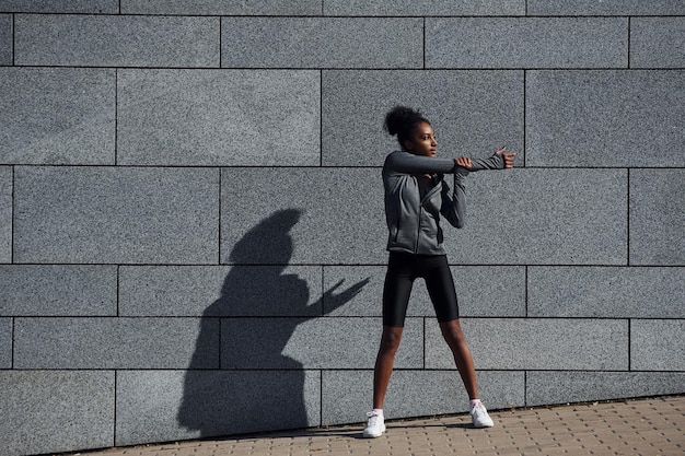 A jovem afro-americana em roupas esportivas tem treino ao ar livre durante o dia