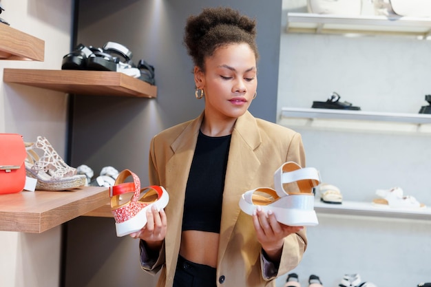 A jovem afro-americana escolhe sapatos de verão em uma loja