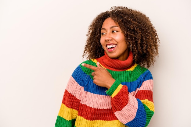 A jovem afro-americana isolada em fundo branco olha de lado sorrindo alegre e agradável