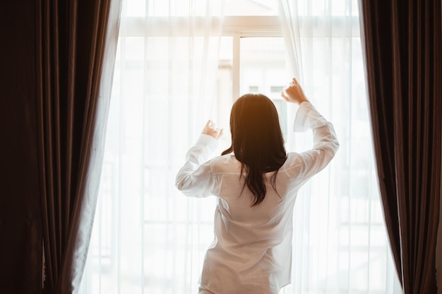 A jovem asiática acorda revigorada pela manhã e relaxa no quarto nas férias. asiático, ásia, relaxe, sozinho, tecnologia, conceito de estilo de vida.