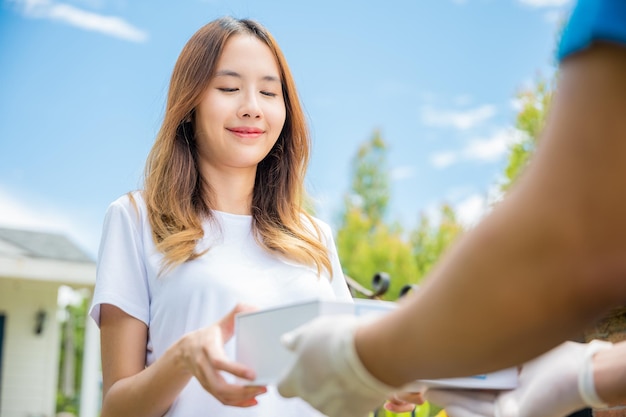 A jovem asiática doente recebe a caixa de farmácia de primeiros socorros do serviço de entrega do hospital, mulher feliz recebendo medicamento do paciente do entregador, conceito on-line de medicina de saúde