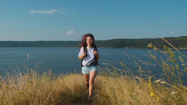 A jovem caminhando com mochila ao longo da bela costa