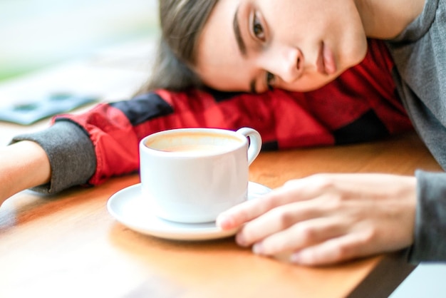 A jovem cansada deitou a cabeça na mesa de café