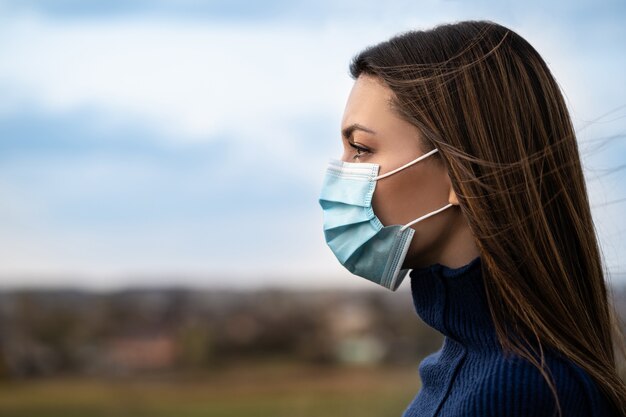 A jovem com máscara médica do lado de fora