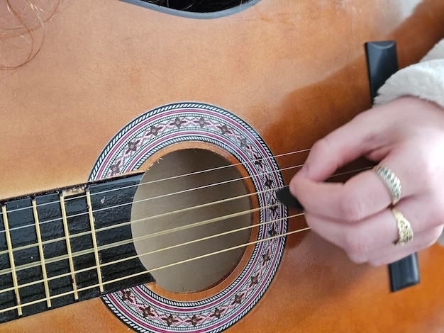 A jovem de cabelos cacheados toca violão com paixão e talento no conforto dela