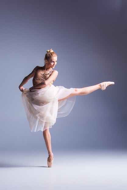 A jovem e bela dançarina de estilo moderno posando em um fundo cinza de estúdio