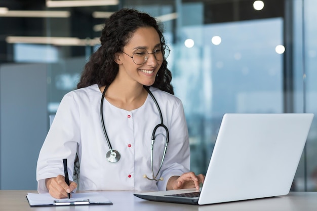 Foto a jovem e bela mulher árabe trabalha na clínica moderna, o médico realiza consultas on-line com