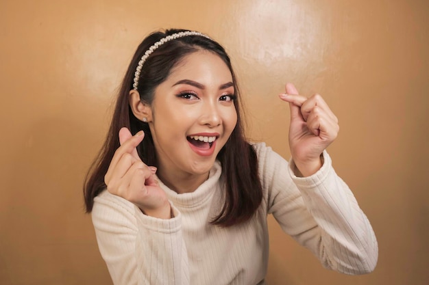 A jovem e bela mulher asiática gesticula com as mãos em forma de coração Sorriso face menina asiática veste camisa branca