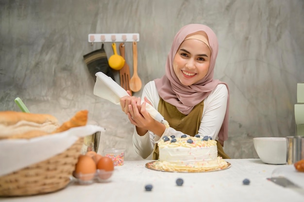 A jovem e bela mulher muçulmana está assando em sua padaria de cozinha e negócios de cafeteria