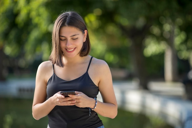 A jovem e bela mulher turca está verificando o celular enquanto sorri