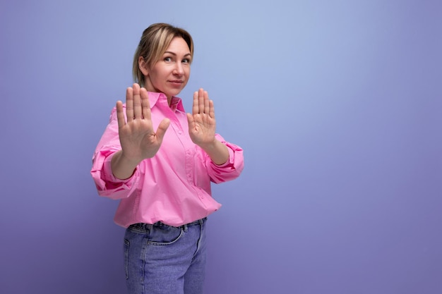 A jovem e bonita trabalhadora de escritório loira europeia vestida com camisa rosa e jeans discorda e mostra