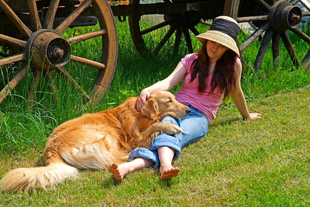 A jovem está brincando com um cão retriever dourado no jardim
