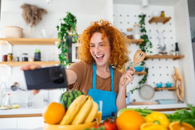 A jovem está na cozinha, ela tem fones de ouvido sem fio, ela está dançando e cantando