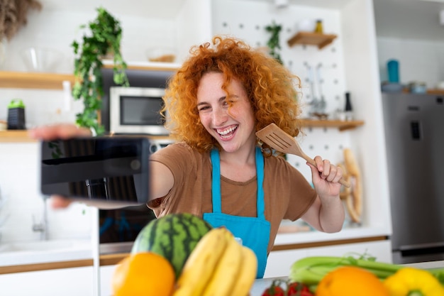 A jovem está na cozinha, ela tem fones de ouvido sem fio, ela está dançando e cantando