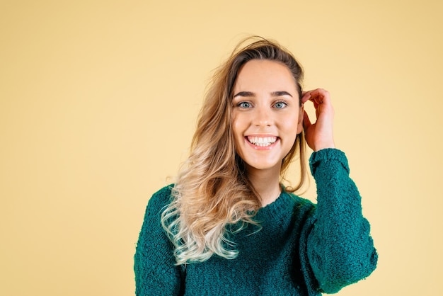 A jovem está olhando para a câmera isolada em fundo amarelo