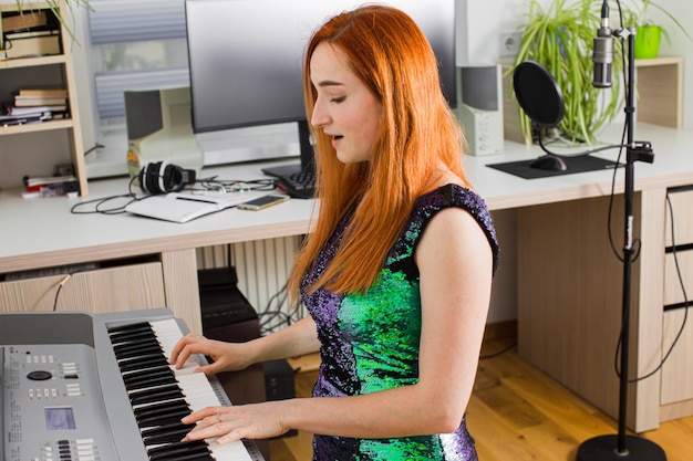 A jovem está tocando no estúdio em um sintetizador