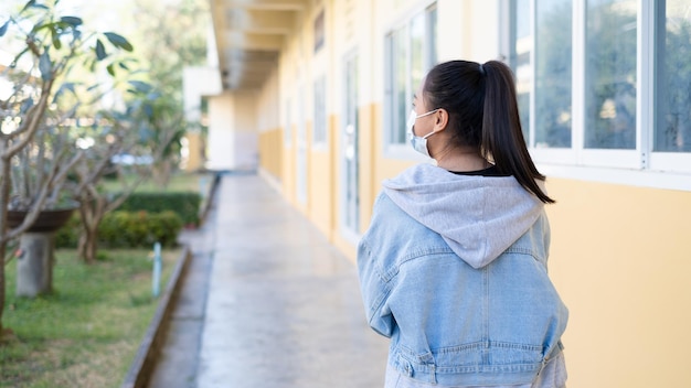 A jovem estudante usa máscara andando na escola.