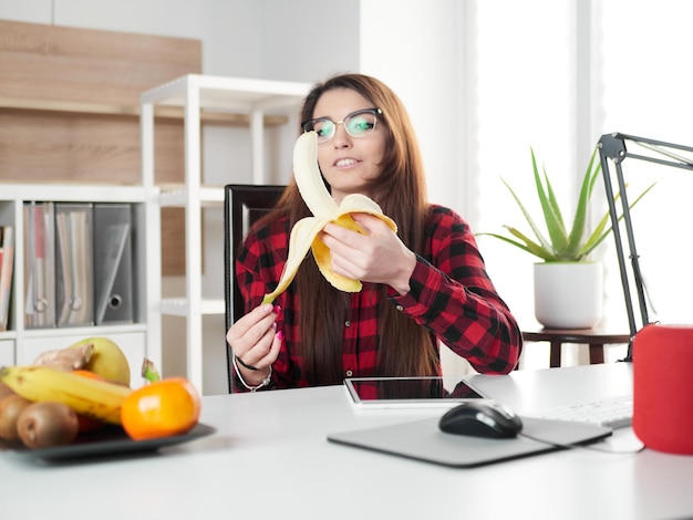 Foto a jovem faz uma pausa e come uma fruta de banana