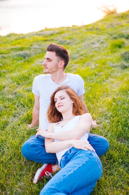 A jovem feliz deitada sobre o namorado no parque de verão