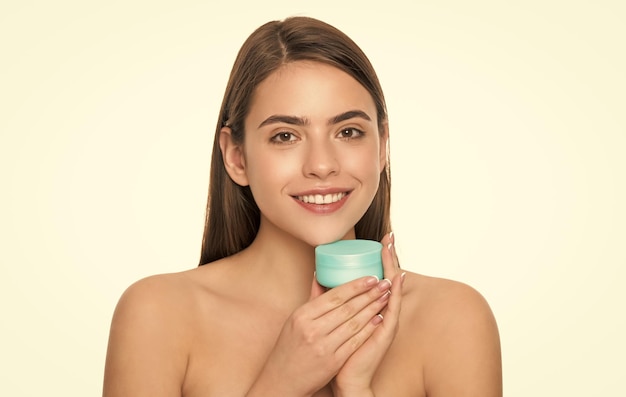 A jovem feliz segura o pote de creme para a pele do rosto isolada no anúncio de fundo branco
