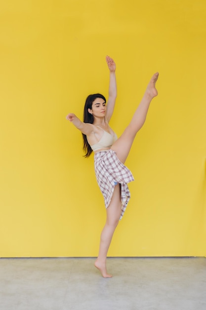 A jovem ginasta bonita realiza vários exercícios em um fundo amarelo