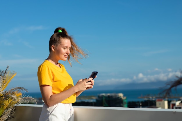 A jovem linda está usando seu celular olhando para a tela do smartphone digitando um