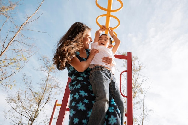 A jovem mãe solteira brinca com o filho no parque ao pôr do sol