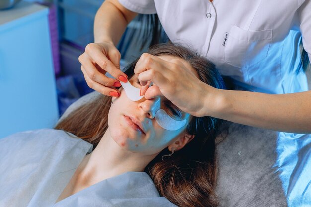 A jovem maravilhosa recebe o procedimento de aplicação de adesivos de tecido de resfriamento de um cosmetologista.