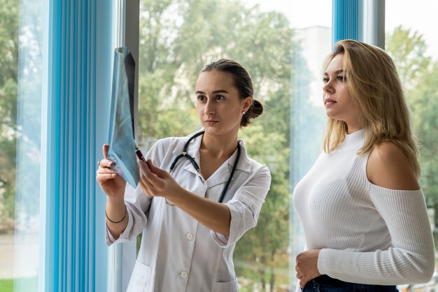 A jovem médica está analisando imagens de raios-x do pulmão da paciente e fazendo consultoria para uma recuperação rápida Covid19