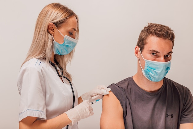 A jovem médica faz uma injeção de vacinação no paciente no braço