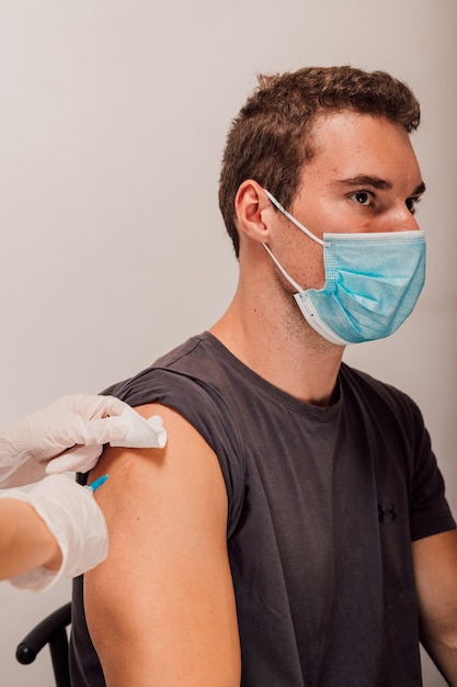 A jovem médica faz uma injeção de vacinação no paciente no braço