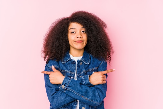 A jovem mulher afro-americana aponta lateralmente, está tentando escolher entre duas opções.