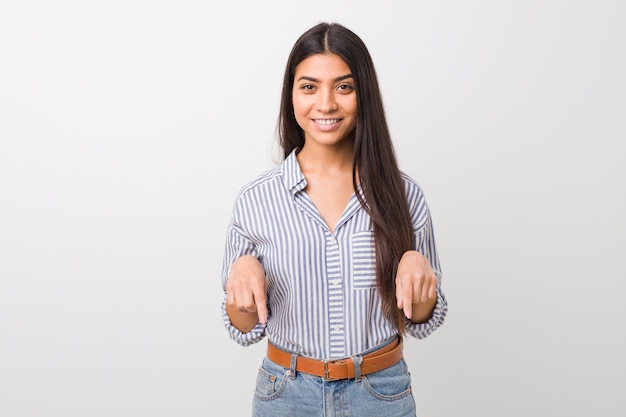 A jovem mulher bonita aponta para baixo com os dedos