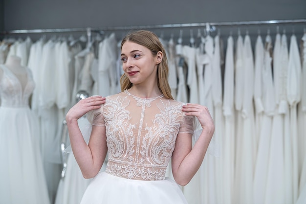 A jovem mulher bonita está tentando vestidos de noiva brancos