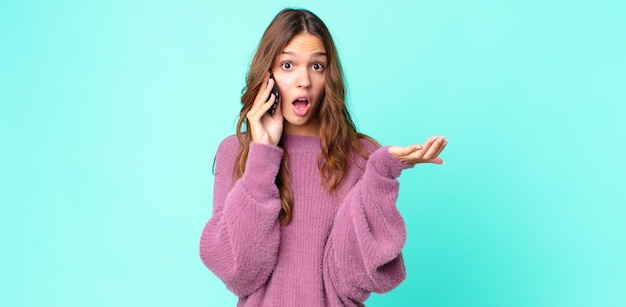 A jovem mulher bonita surpreendeu chocada e surpreendida com uma surpresa inacreditável e usando um smartphone