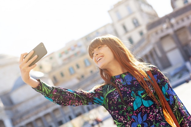 A jovem mulher bonita toma um selfie em Nápoles.