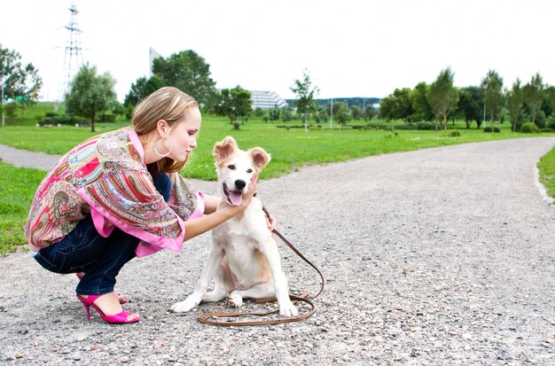 A jovem mulher brincando com cachorro ao ar livre