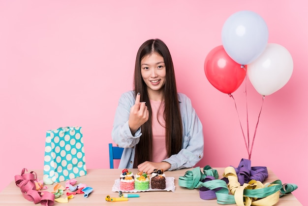 A jovem mulher chinesa que organiza um aniversário isolou apontar com o dedo em você como se convidando se aproximar.