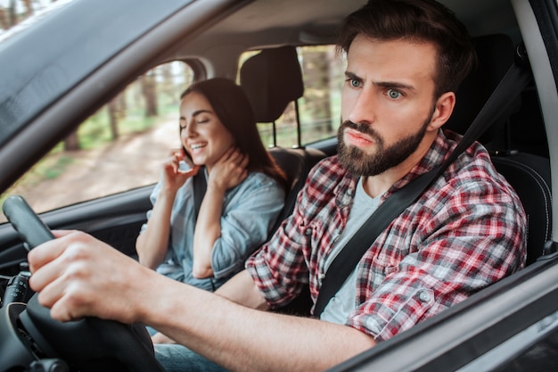 A jovem mulher está sentada além do homem que está dirigindo o carro