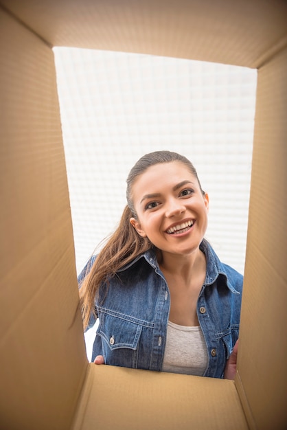 Foto a jovem mulher feliz olhando na caixa.