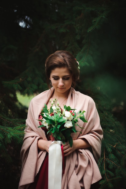 A jovem mulher linda em um vestido de noiva com um buquê