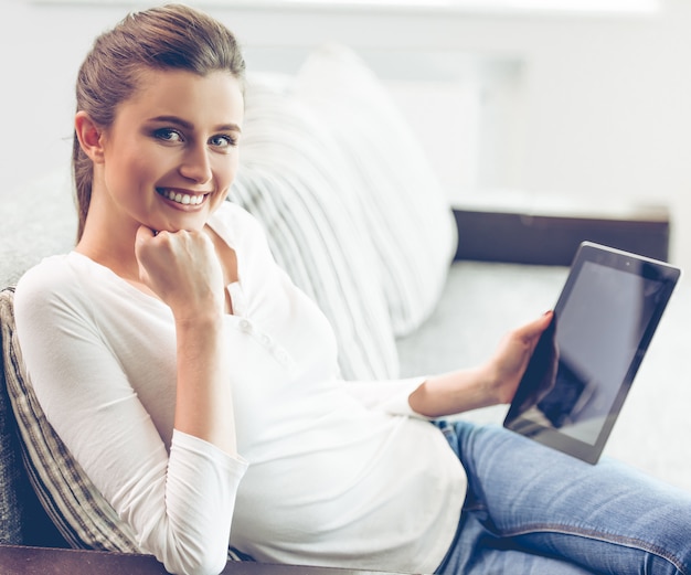 A jovem mulher na roupa ocasional está guardando uma tabuleta digital.