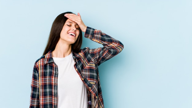 A jovem mulher no azul ri alegremente mantendo as mãos na cabeça. Conceito de felicidade.