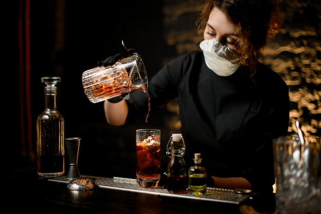 Foto a jovem mulher no bar derrama cuidadosamente coquetel frio no copo