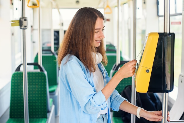 Foto a jovem mulher paga com cartão bancário o transporte público no bonde ou metrô.