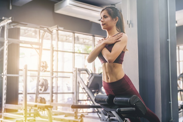 A jovem mulher que fazer se senta levanta o exercício com a máquina no gym da aptidão.
