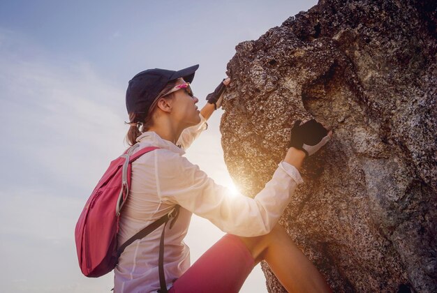 A jovem mulher sobe ao topo nas montanhas perto do oceano