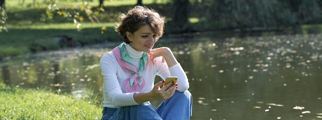 A jovem no parque fala pelo celular Retrato de uma linda garota em estilo francês