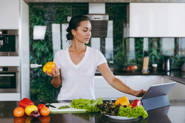 A jovem olhando a receita no laptop na cozinha