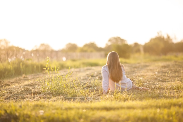 A jovem sentada no campo. o conceito de leveza e serenidade, harmonia com a natureza